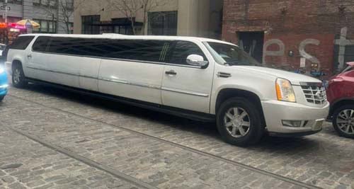 White stretch SUV limousine on cobblestone street