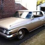 Vintage beige car parked beside brick building