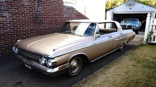 Vintage beige car parked beside brick building