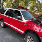 Red SUV with roof light bar, hood open