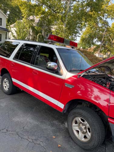 Red SUV with roof light bar, hood open