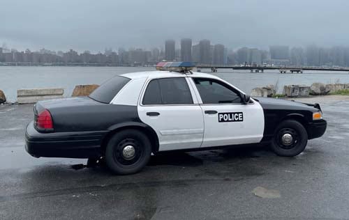 Black and white police car by waterfront skyline