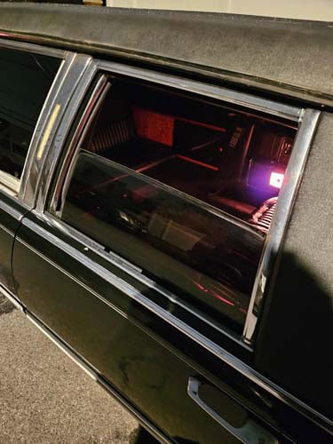 Black limousine with red-lit interior through window