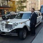 Man in tuxedo beside vintage white limousine