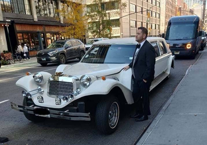 Man in tuxedo beside vintage white limousine