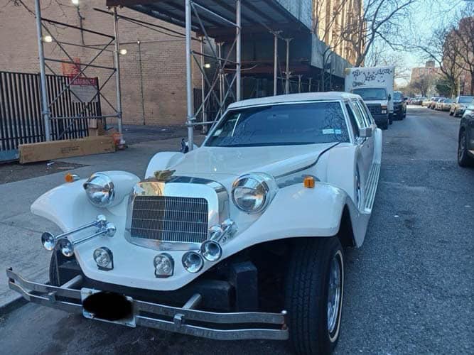 White vintage-style limousine parked on city street
