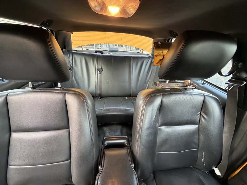 Interior of car with black leather seats and overhead light.