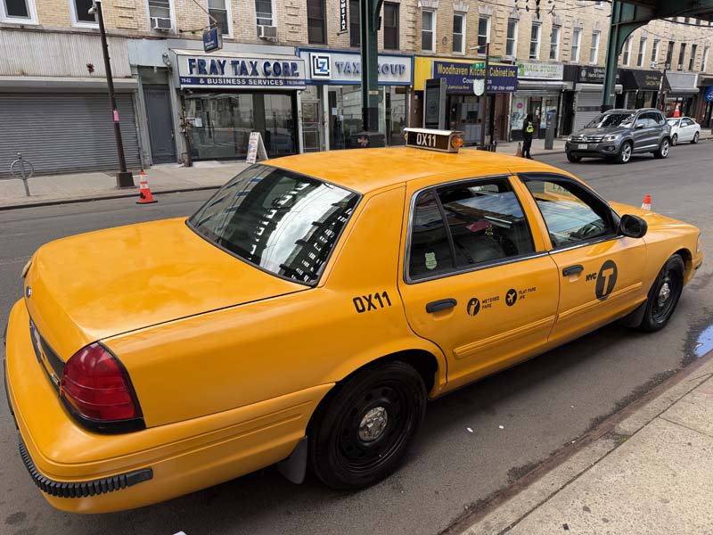 NYC yellow taxi cab on a street with buildings.