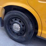 Close-up of a yellow taxi's rear wheel and Michelin tire.