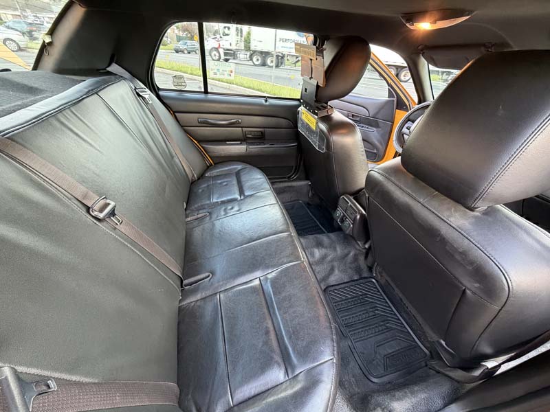 Taxi interior with black rear seats and front partition.