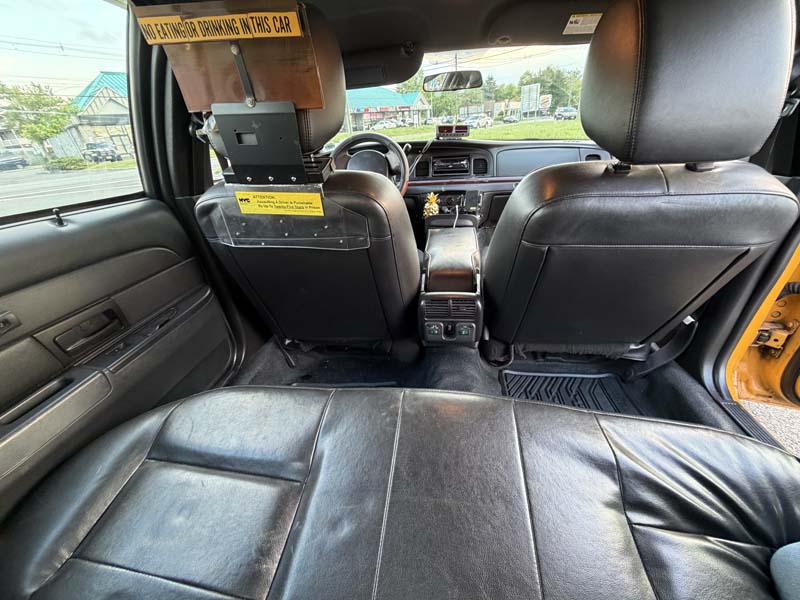 Black leather back seats of a taxi interior.