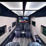 Luxurious conversion van interior with quilted leather seats and TV.