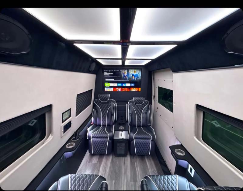 Luxurious conversion van interior with quilted leather seats and TV.