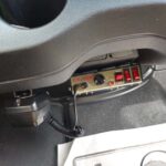 Siren control box mounted under a vehicle dashboard.