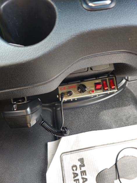 Siren control box mounted under a vehicle dashboard.