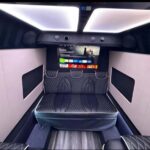 Luxurious van interior with quilted seats and entertainment system.