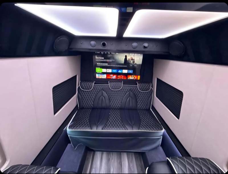 Luxurious van interior with quilted seats and entertainment system.