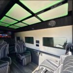 Luxury van interior with green neon ceiling and quilted seats.