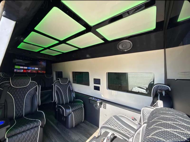 Luxury van interior with green neon ceiling and quilted seats.