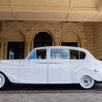 Classic white limousine parked in front of an elegant building.
