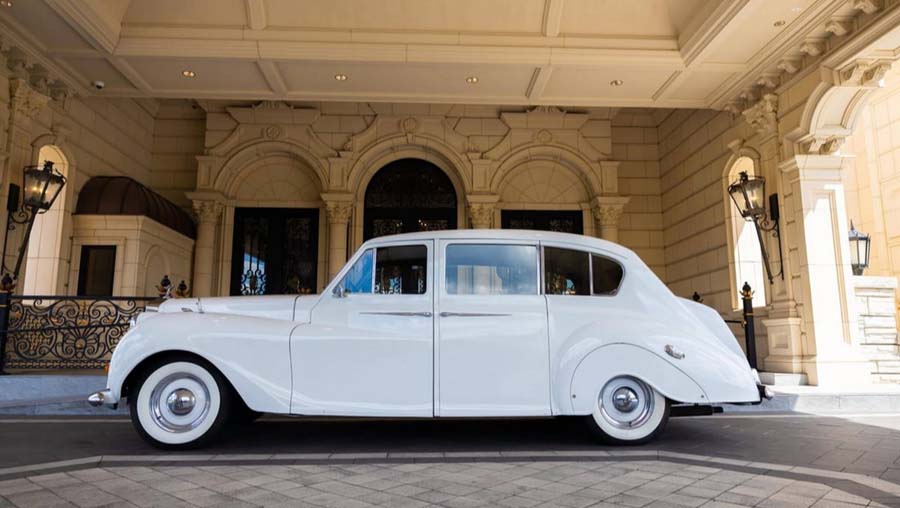 Classic white limousine parked in front of an elegant building.