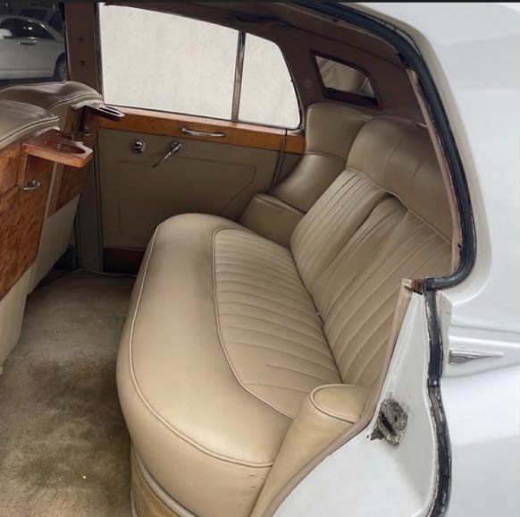Luxurious vintage car back seat with tan leather upholstery.