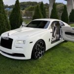 White Rolls-Royce Wraith with open door on green grass.