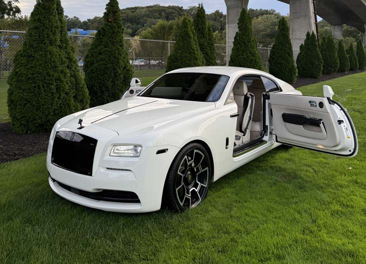 White Rolls-Royce Wraith with open door on green grass.