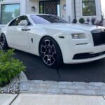 White Rolls Royce with black wheels parked in driveway