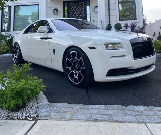 White Rolls Royce with black wheels parked in driveway