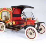 Vintage red circus wagon-style automobile with barred cage