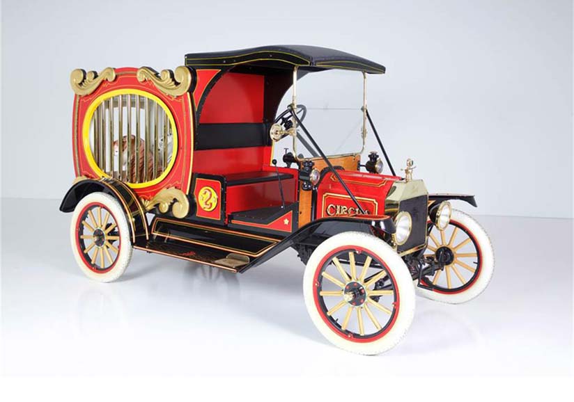 Vintage red circus wagon-style automobile with barred cage