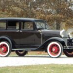 Vintage black 1930s sedan with red wheels outdoors