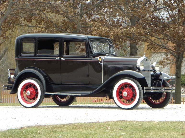 Vintage black 1930s sedan with red wheels outdoors