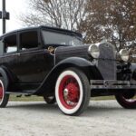 Vintage black car with red wheels and whitewalls