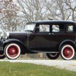 Vintage black 1930s sedan with red wheels outdoors