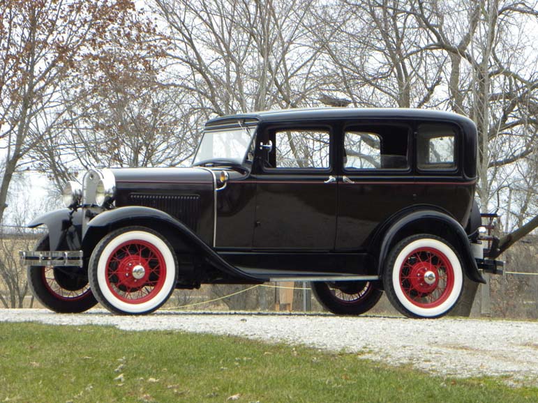 Vintage black 1930s sedan with red wheels outdoors