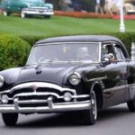 Black vintage 1950s sedan driving on street