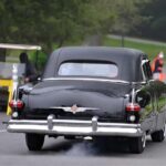 Vintage black car driving on tree-lined road
