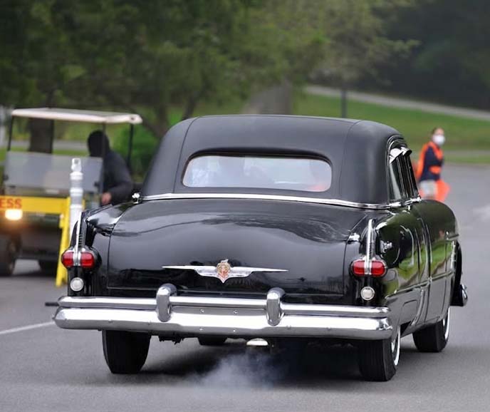 Vintage black car driving on tree-lined road