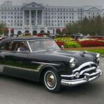 Vintage black car in front of grand white hotel