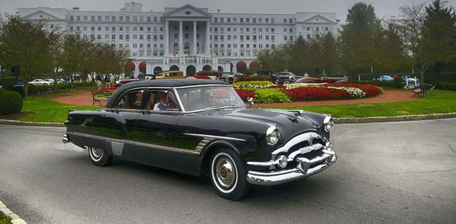 Vintage black car in front of grand white hotel
