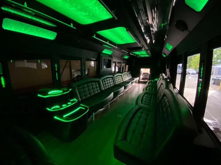Green LED-lit party bus interior with leather seating