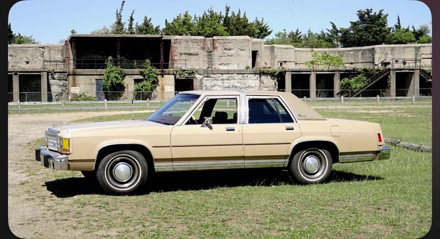 Beige vintage sedan parked before abandoned concrete building