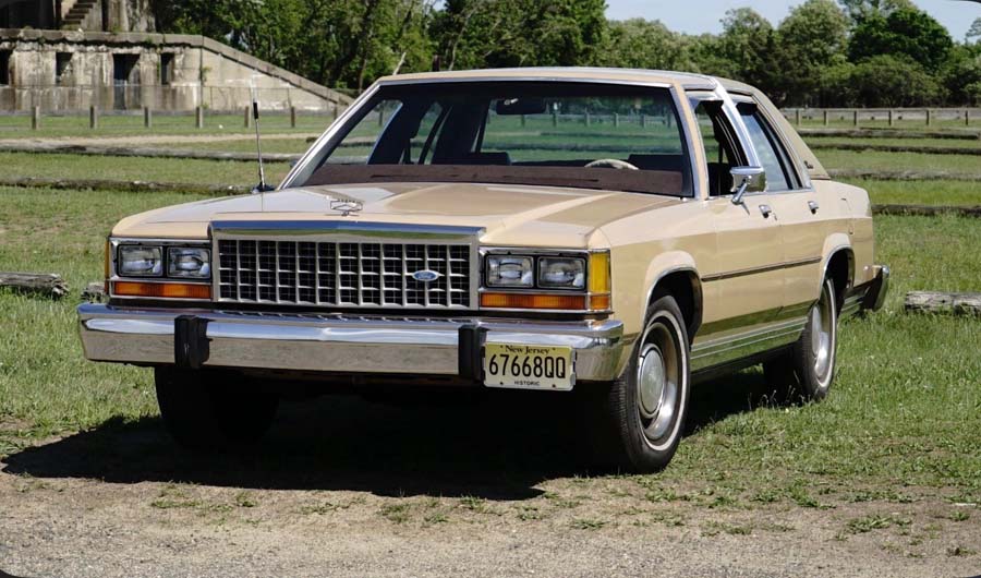 Beige vintage sedan parked on grassy field