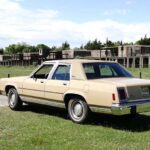 Beige vintage sedan parked near abandoned buildings