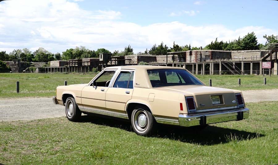 Beige vintage sedan parked near abandoned buildings