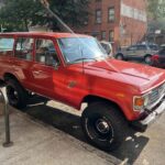 Red vintage Toyota Land Cruiser parked on city street