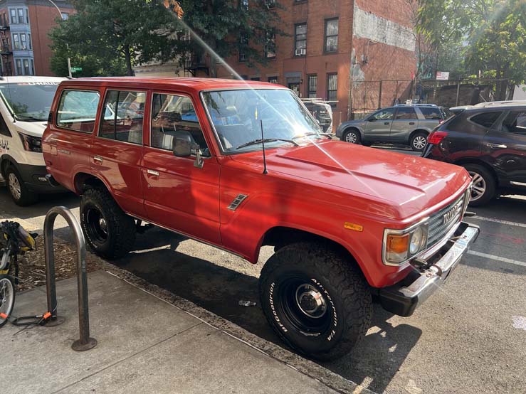 Red vintage Toyota Land Cruiser parked on city street