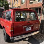 Red vintage Jeep Cherokee parked on city street